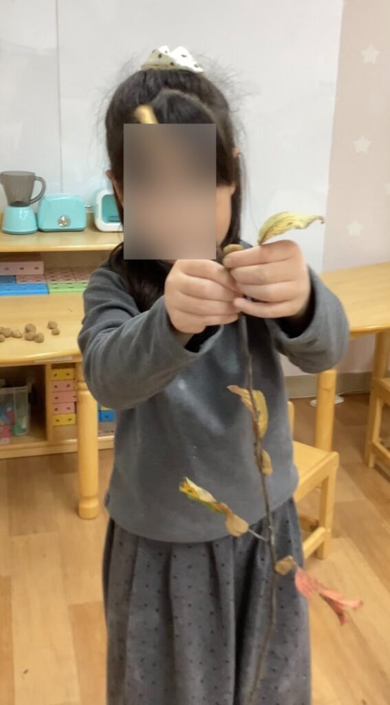 나뭇가지에 점토를 이용하여 낙엽을 붙이는 아이