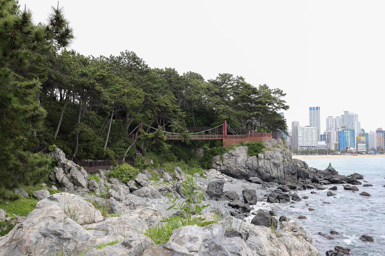 동백섬 해안산책로의 출렁다리와 갯바위, 멀리 해운대 해변