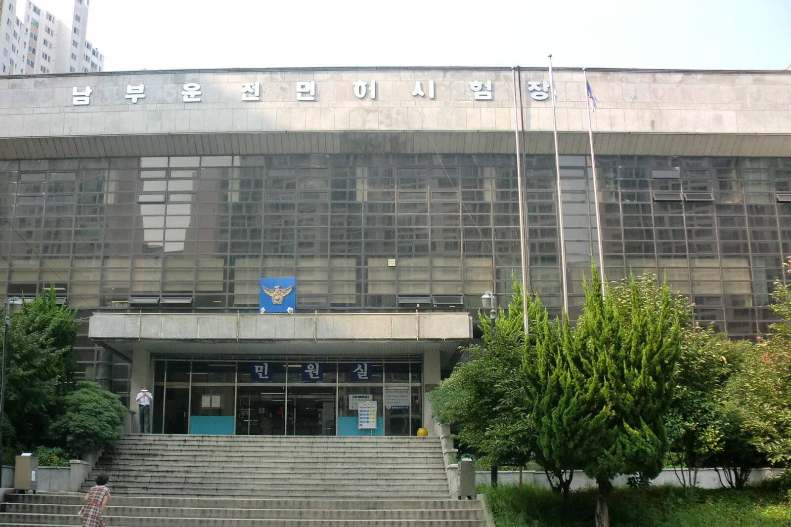 '남부운전면허시험장' 글자와 경찰 마크가 붙은 유리벽 건물, 넓은 계단 위의 '민원실' 입구